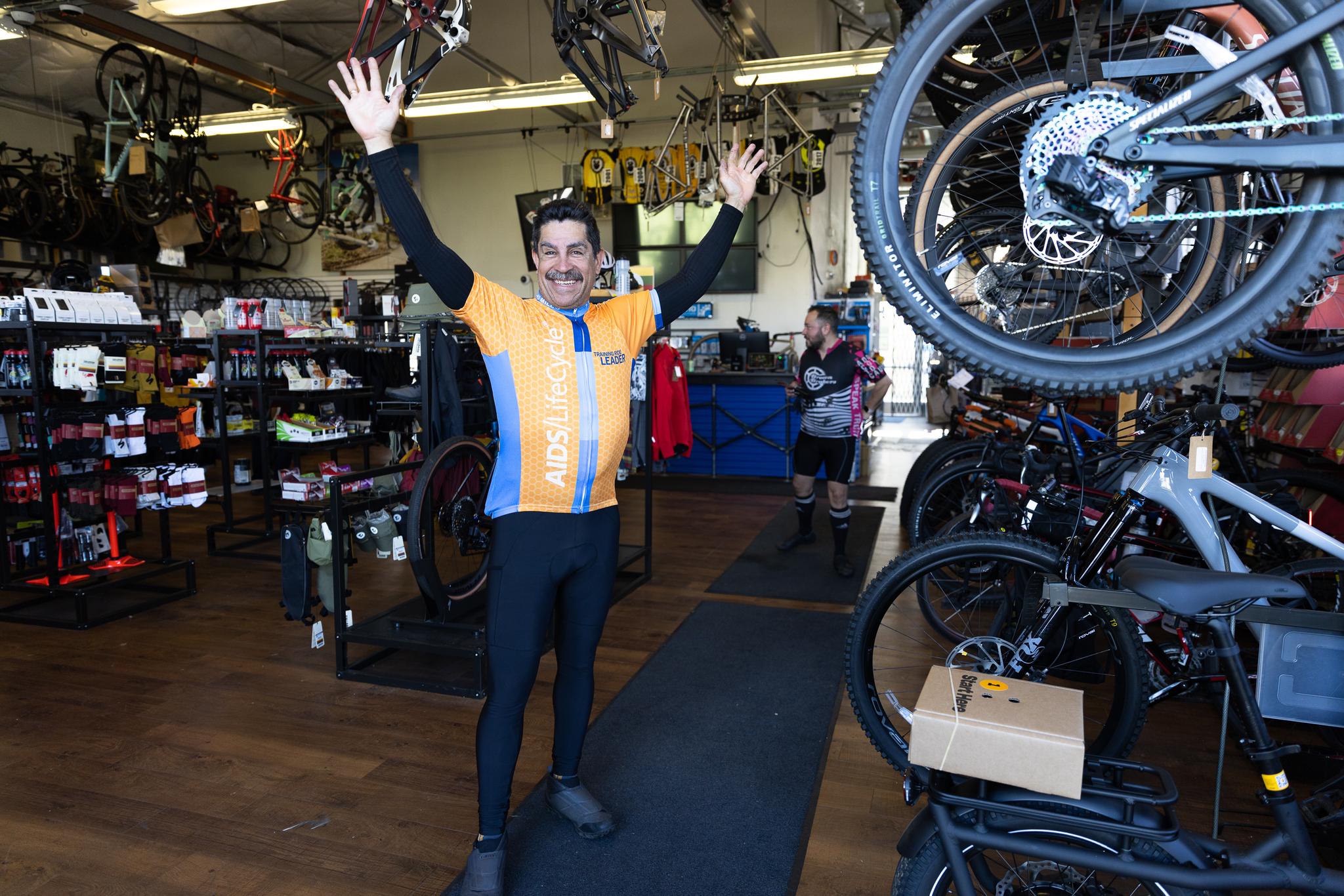 Alt Tag: A man with his hands raised welcomes visitors to Roaring Mouse Cycles in the Presidio. Photo by Myleen Hollero.