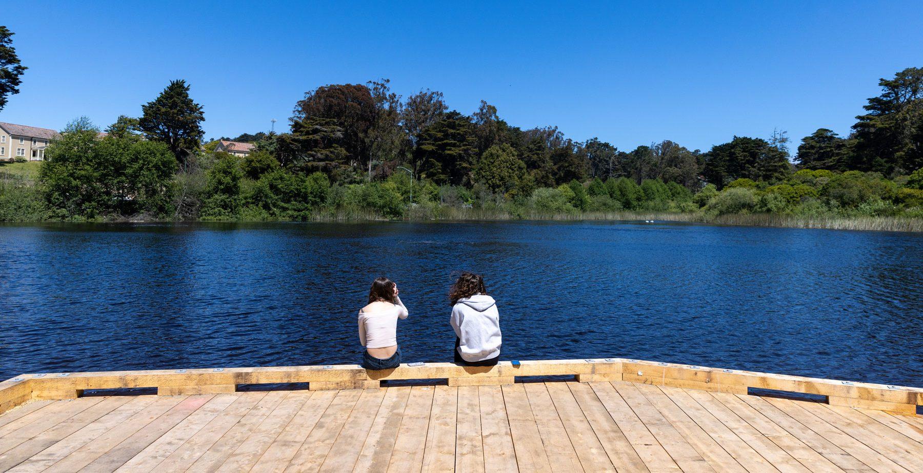 Two people sitting on the ground overlooking Mountain Lake. Photo by Myleen Hollero.
