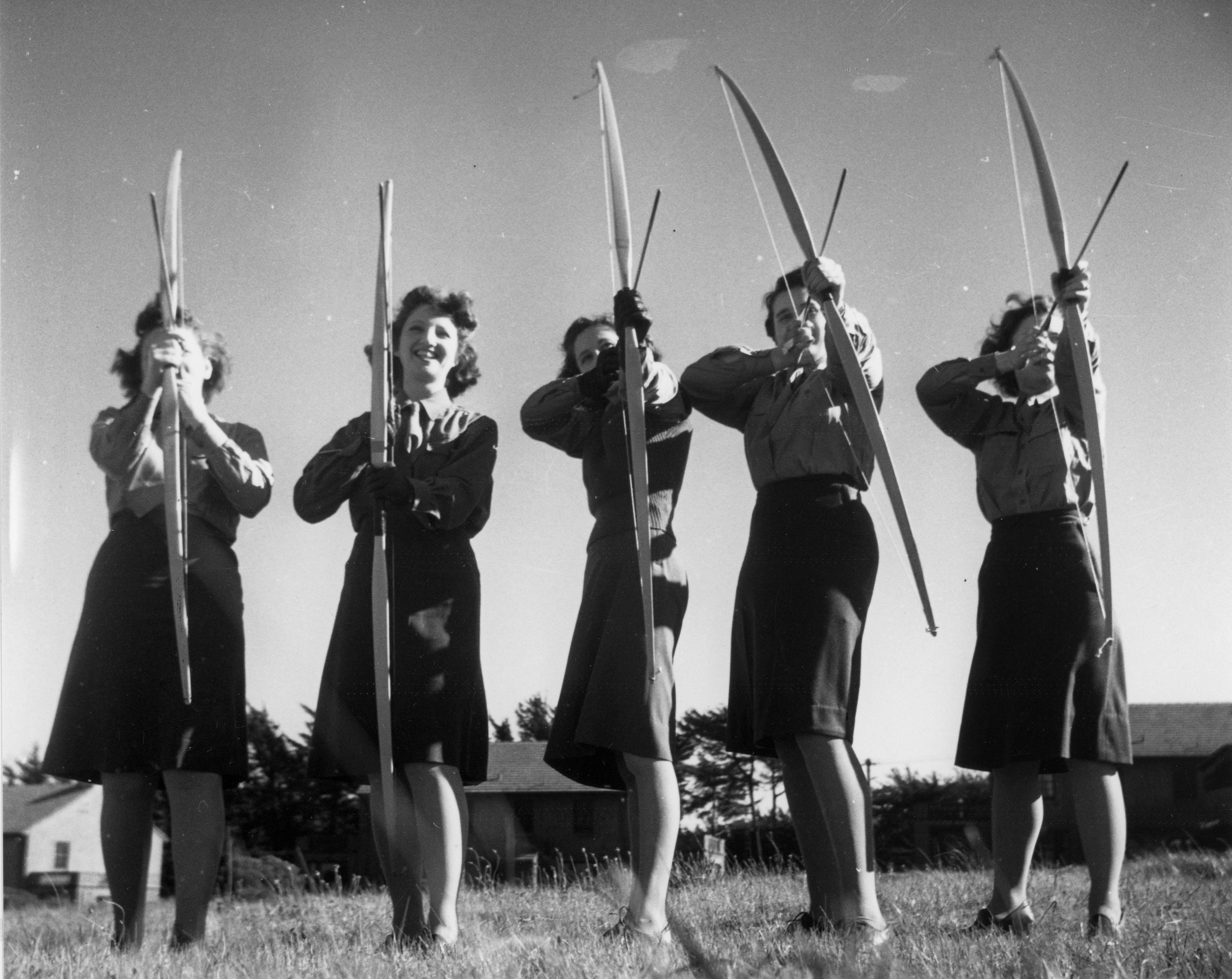 Black and white picture of 5 women holding bows and arrows from the women's army corps.