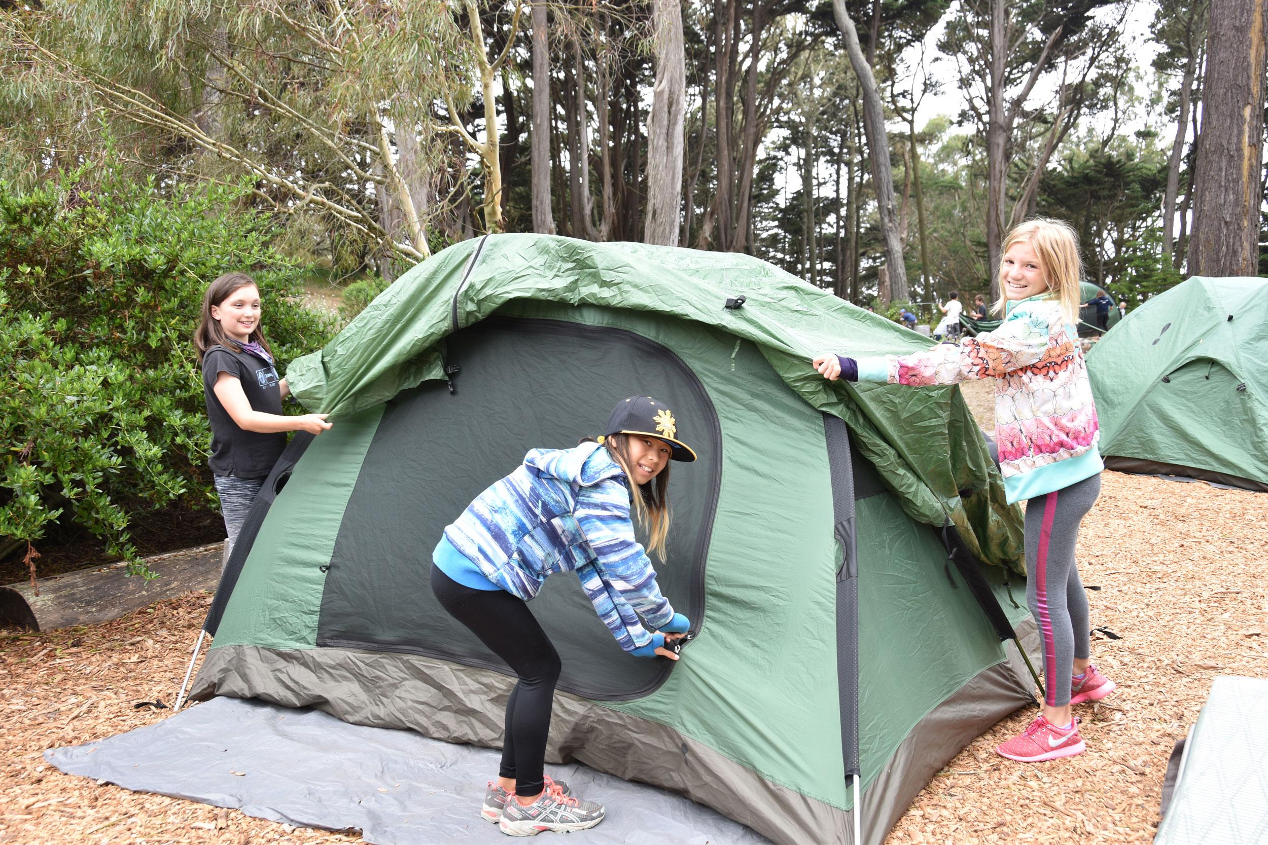 Three kids from YRanger Summer Camp setting up green tent
