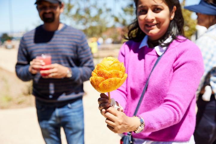 A young girl holds a piece of carved fruit on a stick at Presidio Pop Up. Photo by Rachel Styer.