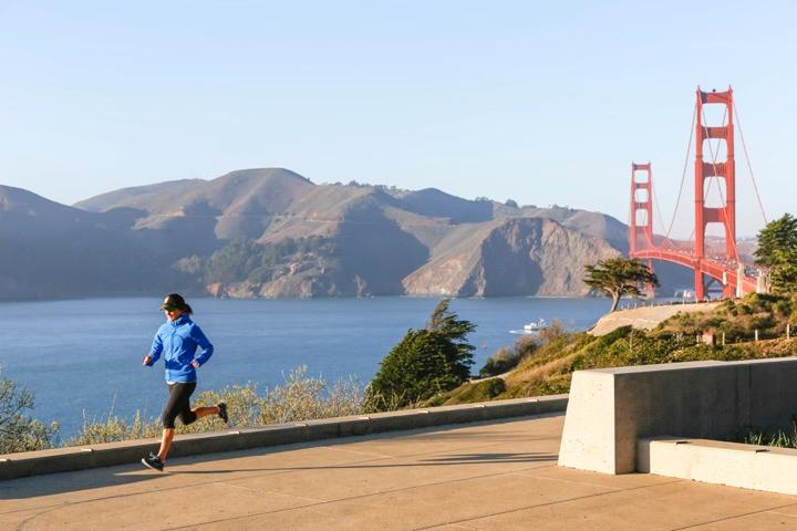 Runner at Pacific Overlook with Golden Gate Bridge to the right.