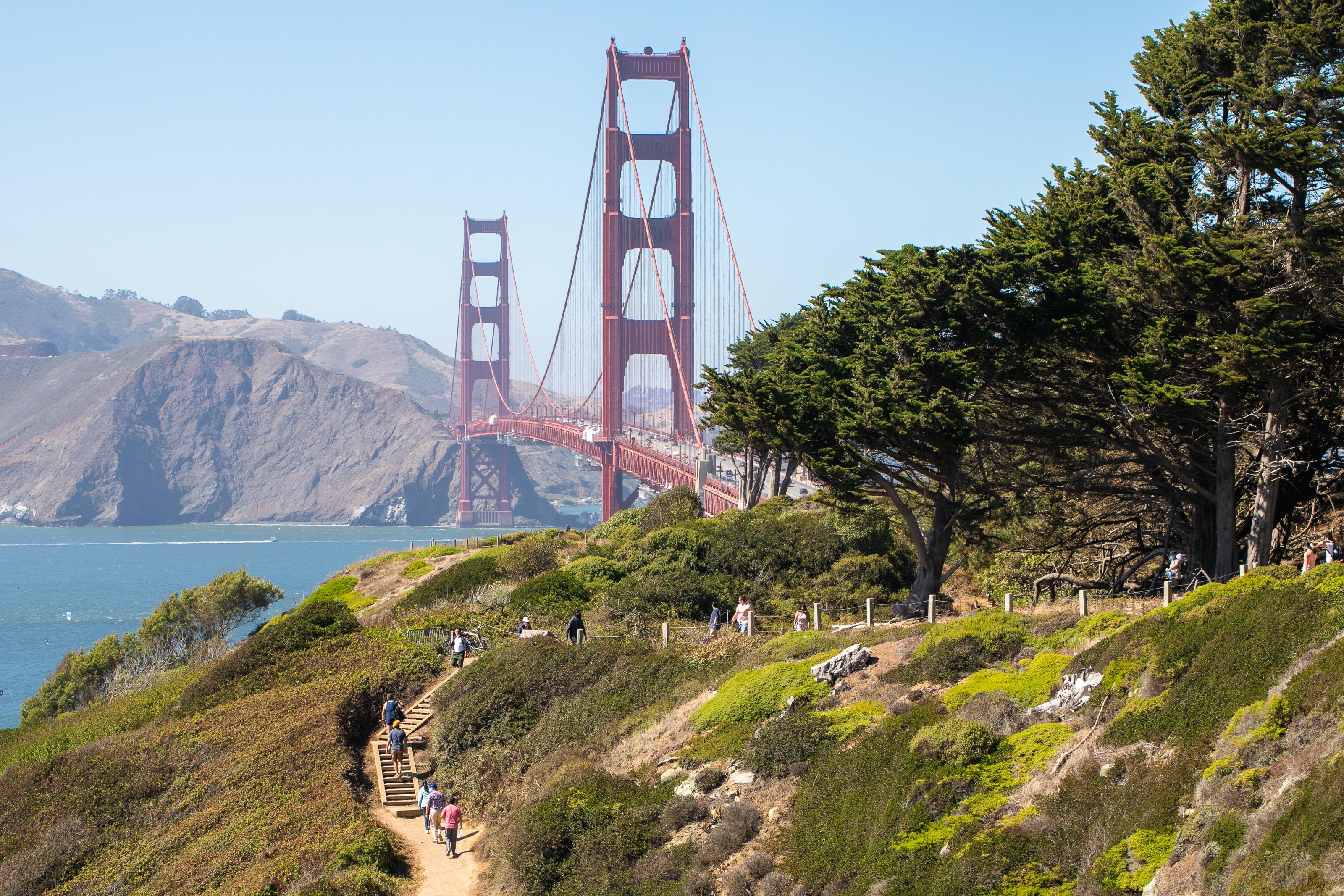 People walking on the Batteries to Bluffs Trail with the Golden Gate Bridge in the background.